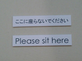 日本語では座るな、英語では座れと書いてある。